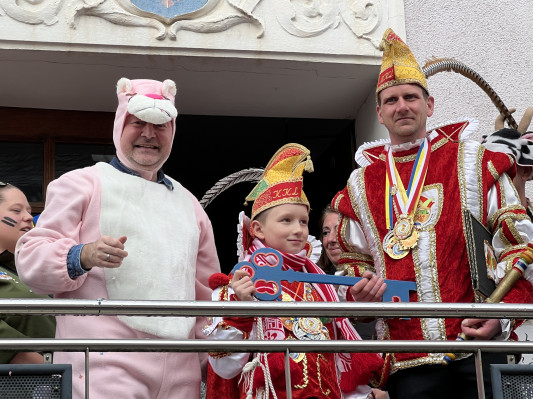 Auf dem Bild ist links der Bürgermeister als Paulchen Panther zu sehen, der den Rathausschlüssel an die Karnevalsprinzen abgibt